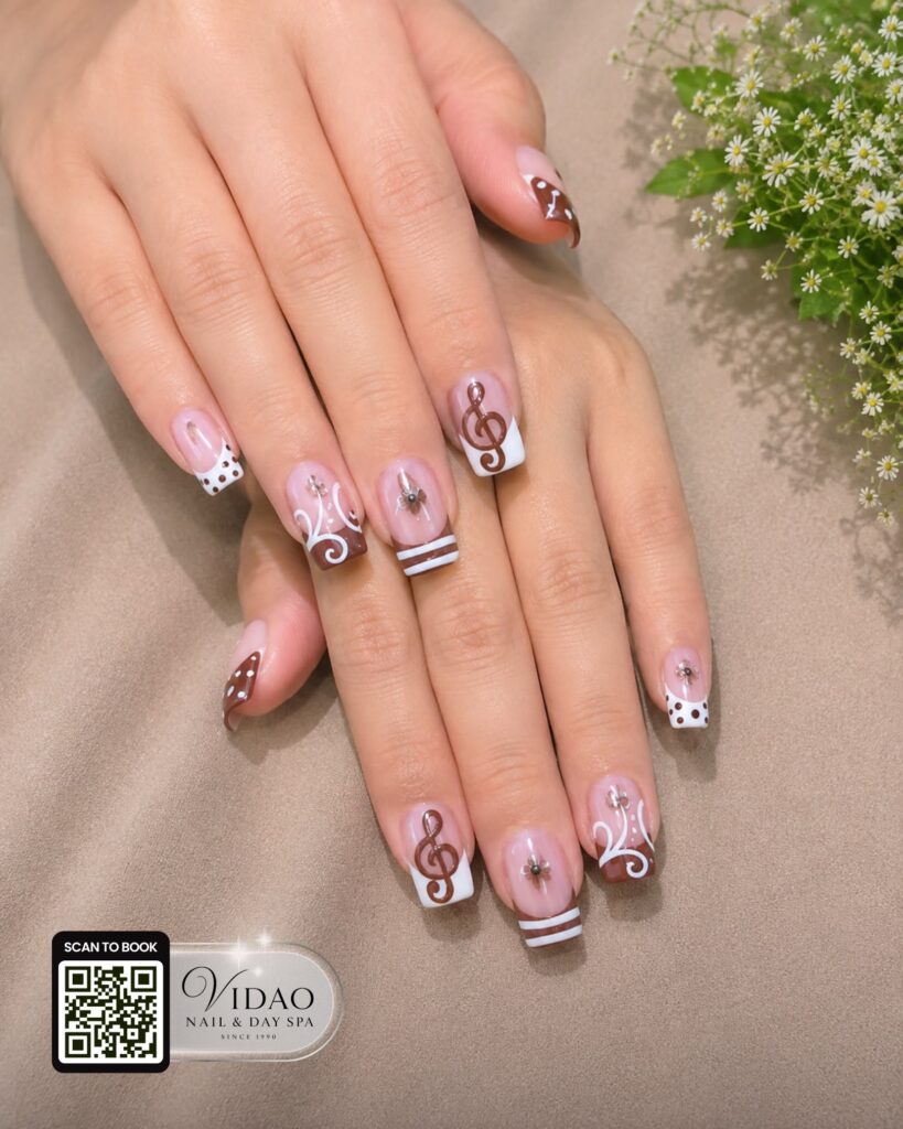Short pink and brown nails with musical notes and stripe accents